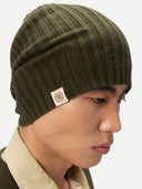 Person wearing a green beanie with a brand logo on a neutral background #color_avocado