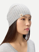 Woman wearing a gray knit beanie with a brand logo on a white background #color_high-rise