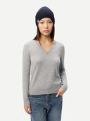 Person wearing a gray sweater, blue jeans, and a navy beanie on a white background  #color_navy-blazer