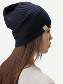 Woman wearing a dark blue knit beanie with a brand logo on a white background  #color_navy-blazer