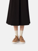 front view of a black skirt and almond color cashmere sneakers with white socks #color_toasted-almond