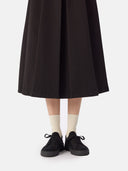 front view of a black skirt and a black knitted sneakers with white socks #color_black