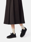 side view of a black skirt and a black knitted sneakers with white socks #color_black