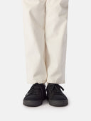 side view of white pants and a black knitted sneakers with white socks #color_black