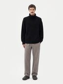 Man wearing a black turtleneck sweater and gray pants on a white background #color_black