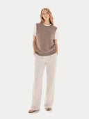 Front-view of woman wearing a brown sleeveless sweater and beige pants on a white background #color_taupe