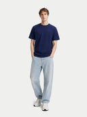 Man wearing a navy t-shirt and light blue jeans on a white background #color_navy