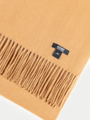 Beige scarf with fringes and a black label on a white background  #color_almond