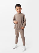 front view of a boy wearing a brown sweater and cashmere pants #color_taupe