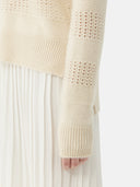 close up of a knitted sweater sleeve with s small holes #color_off-white