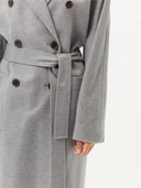 close up bottom side view of a gray double breasted coat with belt and pockets #color_vapor-blue