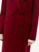 close up of a red double breasted long length cashmere coat #color_bordeaux