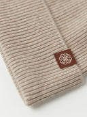 close up of a beige beanie with a small brand logo