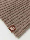 Brown ribbed fabric with a logo tag on a white background. #color_taupe