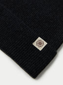 Black knit beanie with a logo tag on a white background #color_black