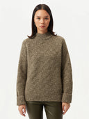A woman wearing a basket-weave cashmere sweater in olive color, with a high neck, long sleeves, and ribbed hem.  #color_capulet-olive