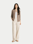 Woman wearing a brown crew neck cardigan, white top, and beige pants on a white background #color_taupe