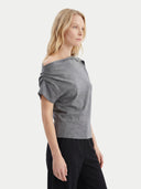 close up side view of a woman wearing a gray off-shoulder top and black pants on a white background #color_steel-gray