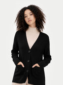 Woman wearing a black v-neck cardigan with buttons over a beige turtleneck on a white background #color_black