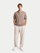 Man wearing a brown polo shirt and beige pants on a white background #color_nomad