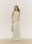 A female model wearing a beige lightweight cashmere silk turtleneck and matching skirt, standing against a white background. #color_marshmallow