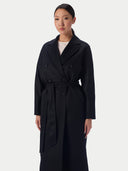 Model wearing black women's cashmere coat, double-breasted front with wide lapels and self-tie belt, close view
