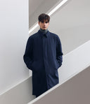 Man wearing a navy coat in a minimalistic setting