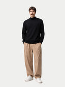 front view of a man wearing a black turtleneck, beige pants, and white sneakers on a white background #color_black