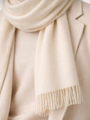 Beige scarf with fringe detail draped over a light-colored garment. #color_off-white