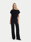 front view of a woman wearing a black off-shoulder top and wide-leg pants on a white background #color_black