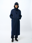 Person wearing a long navy coat and hat on a white background #color_navy-blazer