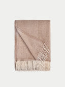Beige woven blanket with white fringe on a light gray background.