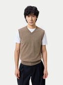 Person wearing a brown vest over a white shirt with black pants on a light background #color_taupe