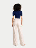 back view of a person wearing a navy top and beige pants on a white background #color_mood-indigo