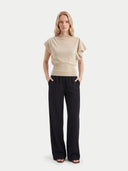 Woman wearing a beige short sleeve, boat neck top and black pants on a white background #color_beige