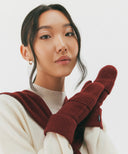 Person wearing a white sweater and red gloves with a white background