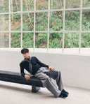 Person sitting on a bench in a room with large windows showing greenery outside