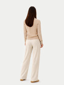 back view of a Woman wearing a beige sweater and white pants on a white background #color_beige