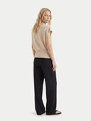 back view of a woman wearing a beige short-sleeve cashmere top and black pants on a white background #color_beige