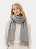 Woman wearing a gray scarf with fringe on a light background  #color_dim-gray