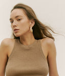 Woman wearing a beige ribbed tank top against a neutral background