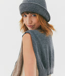Woman wearing a gray knit hat and sleeveless sweater on a white background