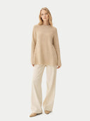 Woman wearing a beige sweater and pants on a white background #color_warm-grey