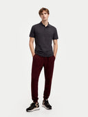 front view of a man wearing a dark gray polo shirt and maroon pants on a white background #color_charcoal