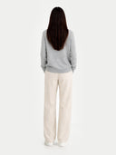 back view of a Person wearing a gray sweater and white pants on a light gray background #color_vapor-blue