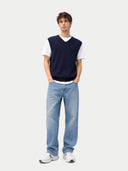 front view of a man wearing a navy sweater vest over a white shirt with light blue jeans on a white background #color_navy-blazer