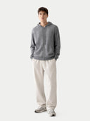 Person wearing a gray zip-up hoodie and light gray sweatpants on a white background #color_dim-gray