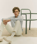 Person sitting on a light-colored floor with a green chair in the background