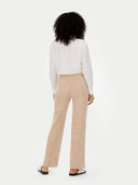 back view of a woman wearing a white blouse and beige pants on a white background #color_beige