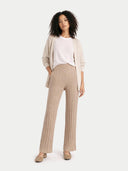 Woman wearing a beige cardigan, white shirt, and beige pants on a white background #color_warm-grey